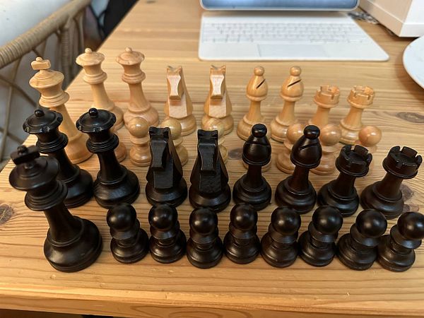 Elegant chess set made of polished wood with carved pieces on a hardwood board.