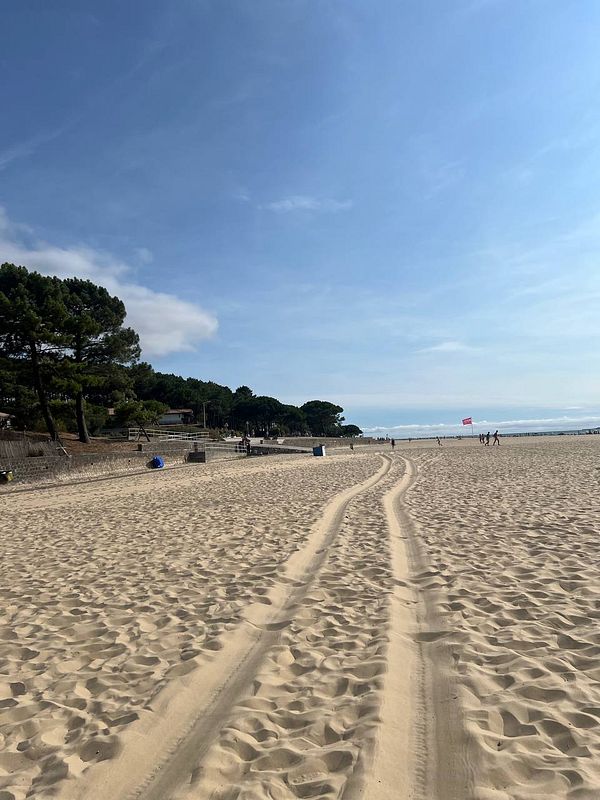 A serene French beach scene with sandy paths and distant beachgoers.