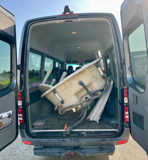 A large, white jacuzzi is loaded in the back of a van.