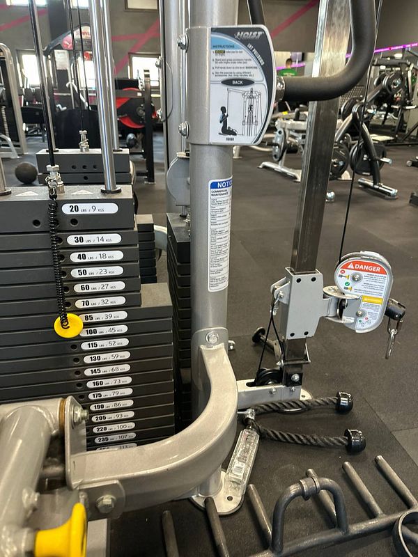A gym cable machine with adjustable weight stacks and exercise instructions.