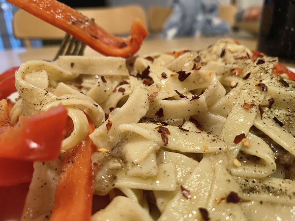 A close-up view of cheese and pepper pasta garnished with red pepper and spices.