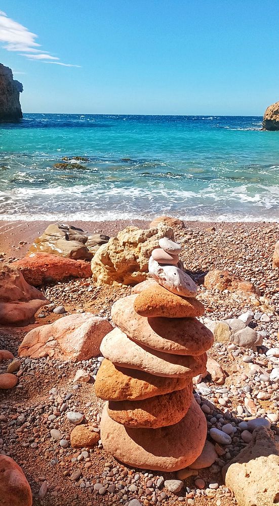 Hand holding a white cup filled with coffee with latte art on top, set against a warm, softly blurred background.