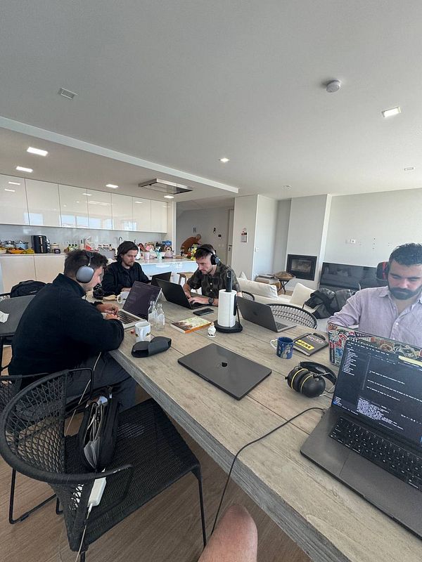 A group of four individuals is engaged in a coworking session at a modern table in a well-lit room.