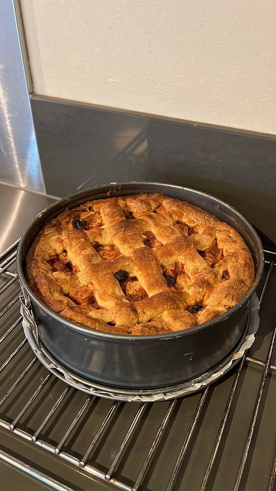 A freshly baked apple pie is cooling on a wire rack.