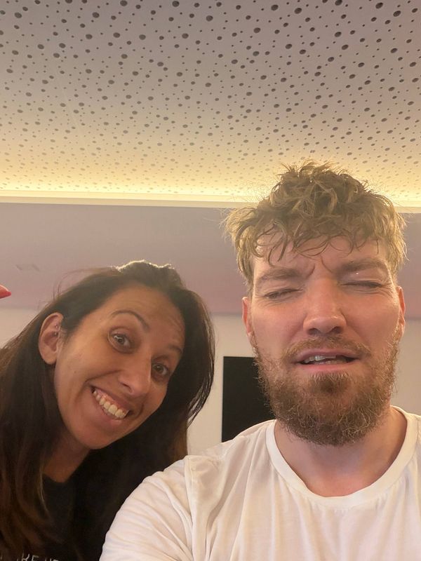 Two people after a workout session in a gym, one smiling and the other looking exhausted.