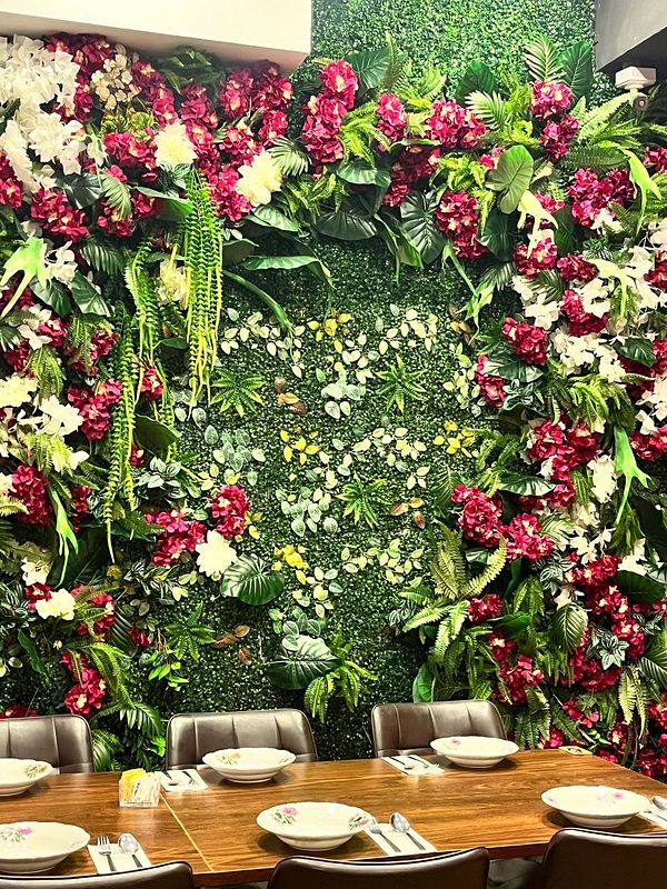 A vibrant floral wall decor enhances a dining area with a wooden table set for a meal.