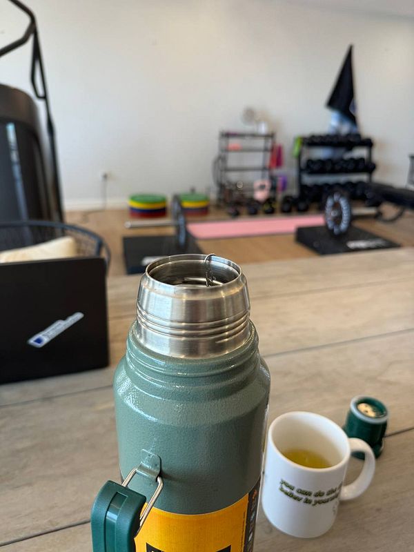 A close-up view of a thermos with a gym setting in the background.
