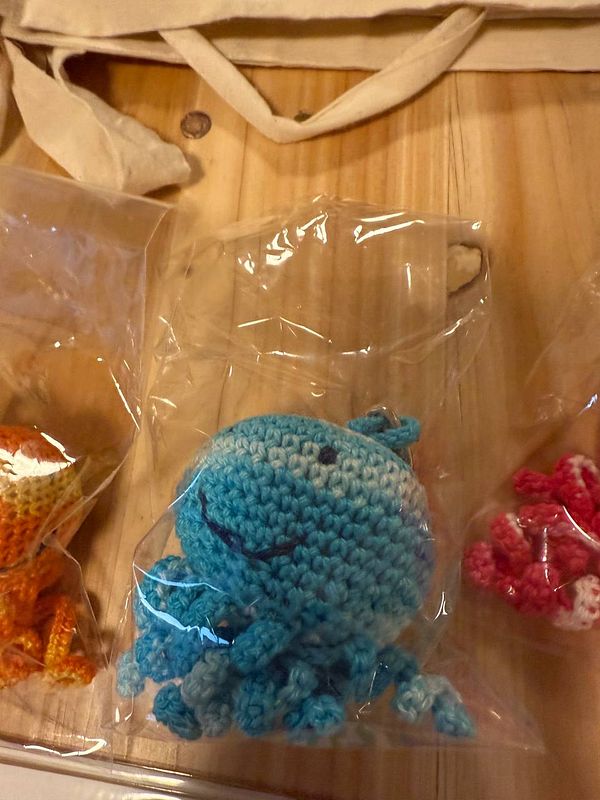 A collection of crocheted sea creatures displayed in plastic packaging on a wooden surface.