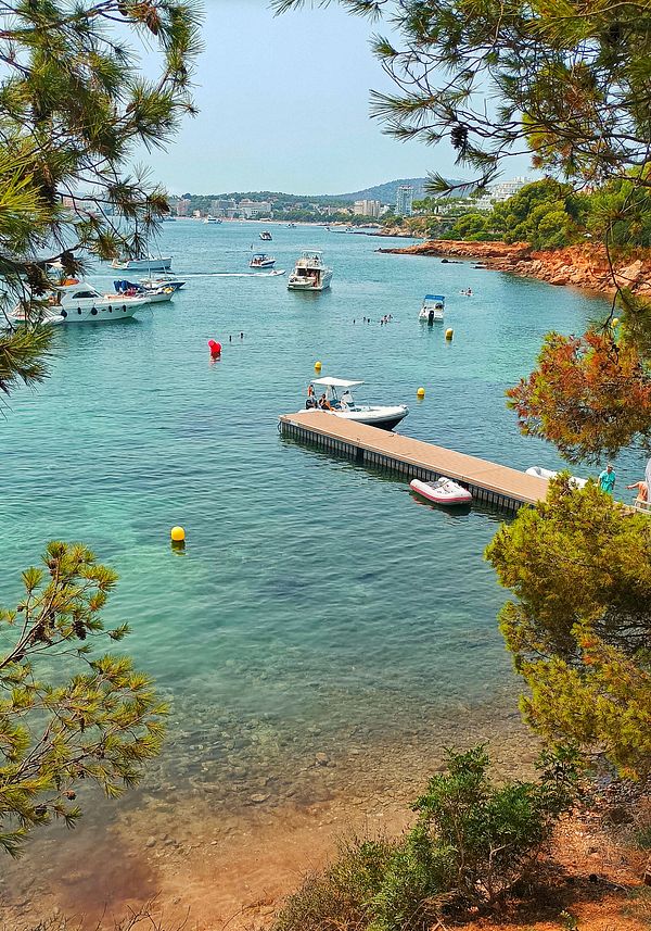 A scenic view of a tranquil bay with boats and people enjoying the water.