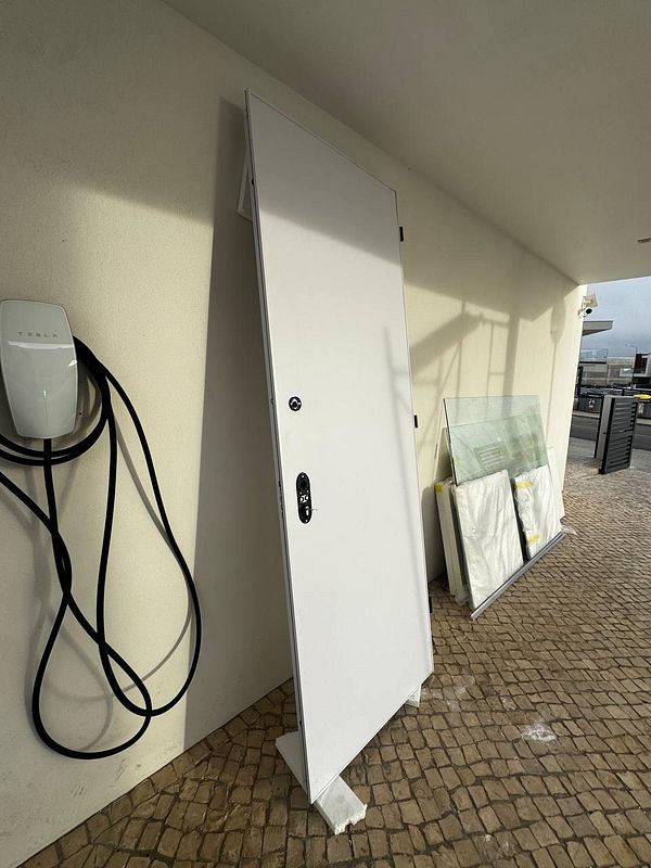 A custom-made solid steel door is propped up against a wall, ready for installation.