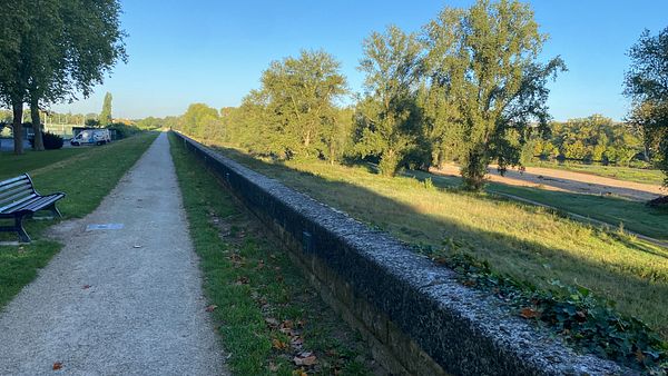 A scenic pathway lined with trees and a stone wall, ideal for a quick run.