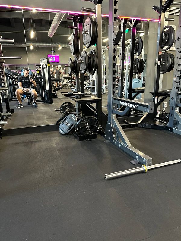 A gym interior featuring workout equipment and a person resting.