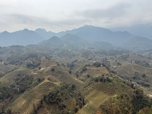 A panoramic view of terraced mountains under a cloudy sky.