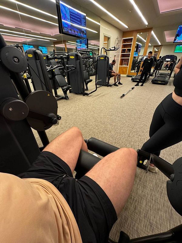 A gym scene featuring workout equipment and individuals engaged in fitness activities.