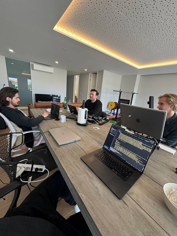 A group of three individuals is engaged in a coworking session at a modern workspace.