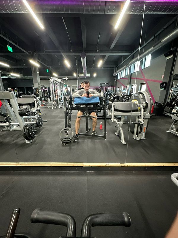 A person is seated at a gym machine, preparing for a workout.