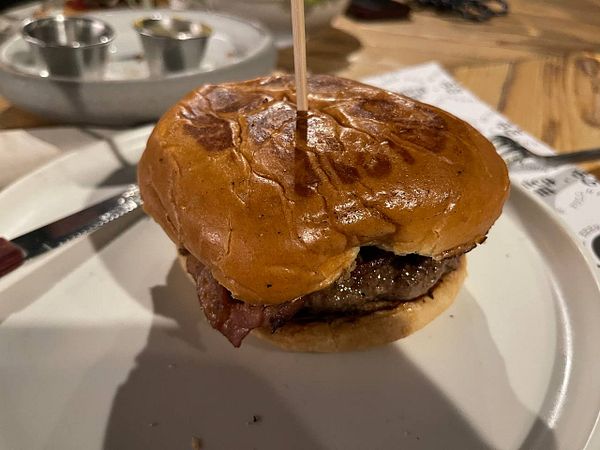 A close-up of a burger on a plate with a wooden skewer.