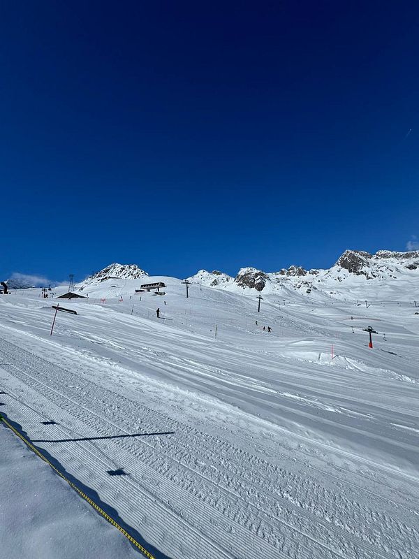 A scenic view of a ski resort with snow-covered slopes and clear blue skies.