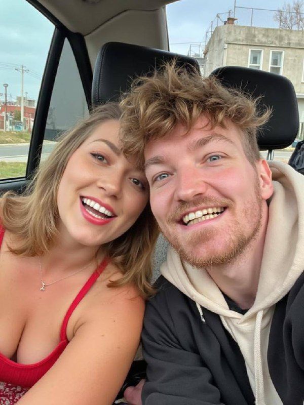 A cheerful couple takes a selfie inside a car.