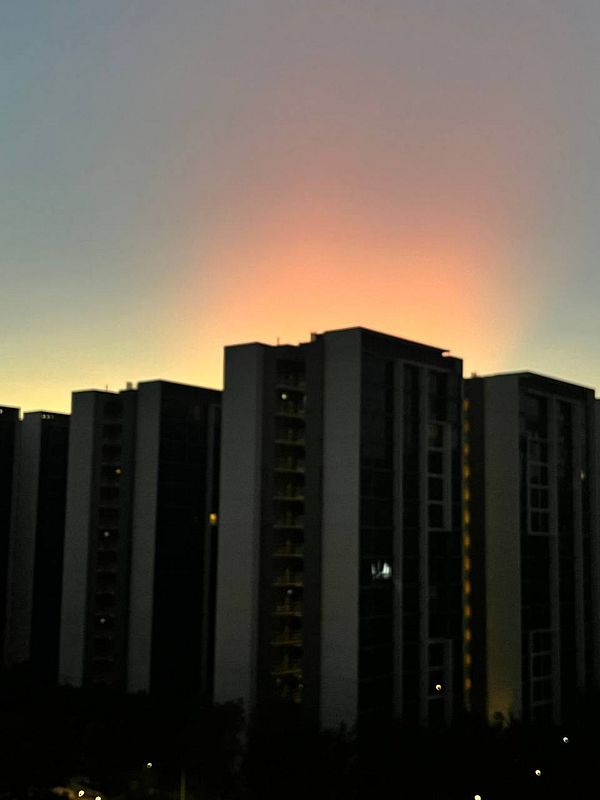 A serene evening sky with a gradient of colors above tall buildings.
