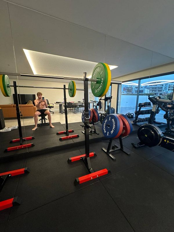 A home gym setup featuring weightlifting equipment and a person resting.