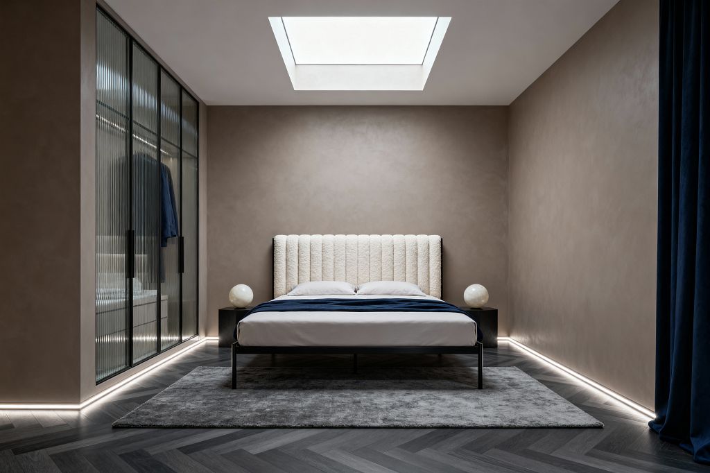A symmetrical modern bedroom features a low black metal bed with a vertical‑channeled cream bouclé headboard centered beneath a large skylight. Taupe plaster walls, perimeter LED strip lighting, a gray rug over dark herringbone wood flooring, black cube nightstands topped with opal glass globe lamps, a left-side wardrobe with black-framed fluted glass doors, and deep navy bedding and curtain complete the minimalist, calming scheme.