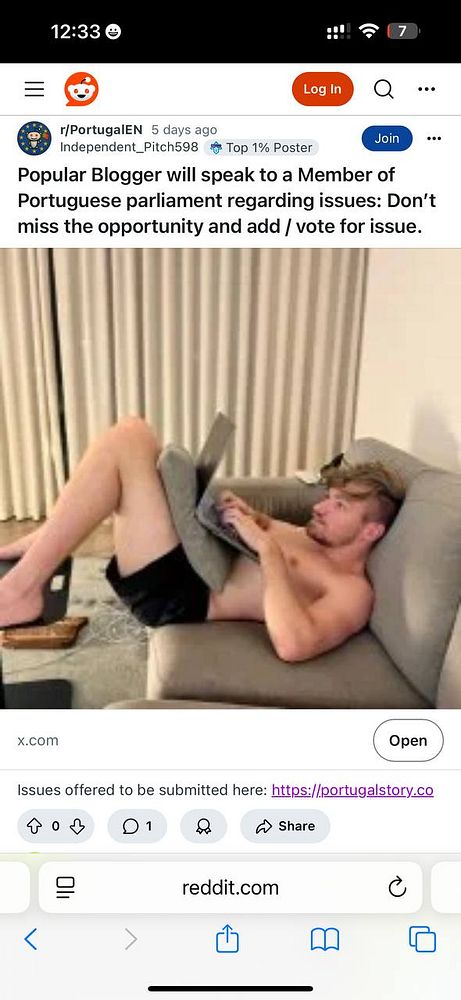 A young man is lounging on a couch while using a laptop.