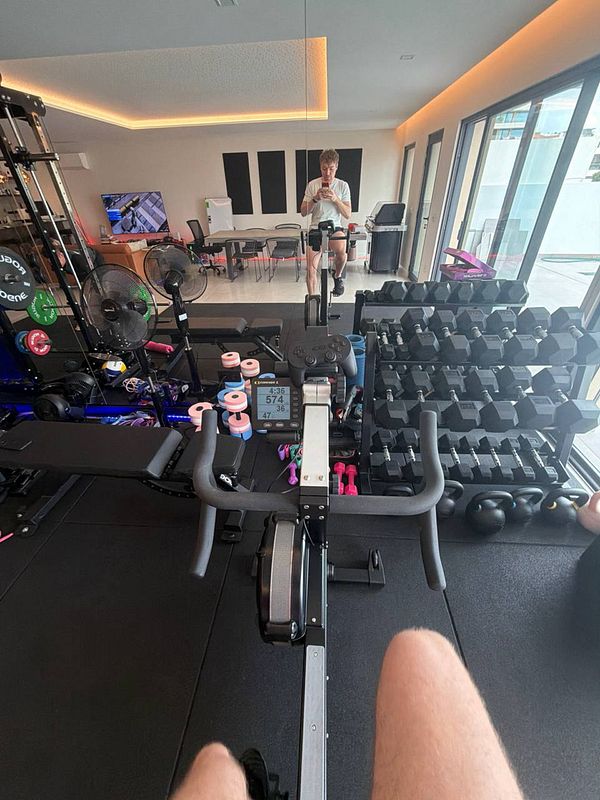 A photo of a narrow urban alleyway with a mix of residential and commercial elements, featuring plants and parked motorbikes.