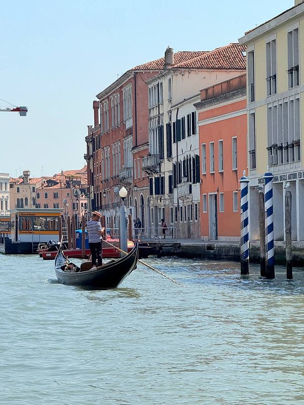 A gondola navigates through the canals of Venice, surrounded by historic buildings.