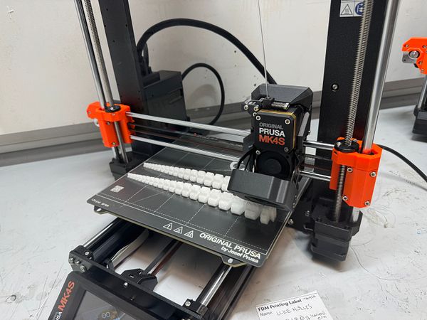 A 3D printer is actively printing a set of tentacles on its build plate.