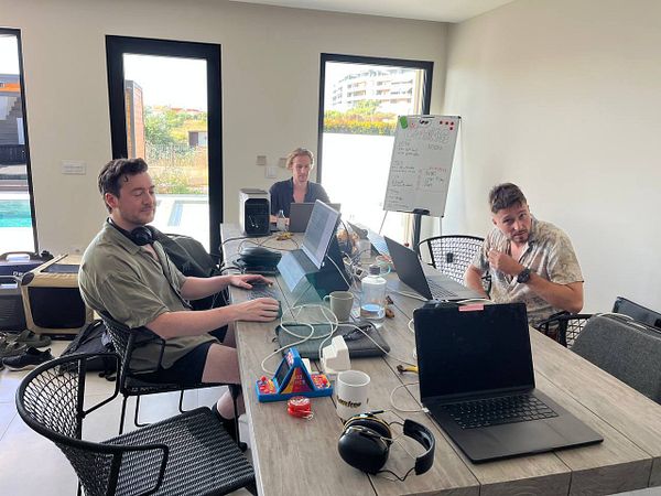 A group of three individuals is working together in a modern coworking space.