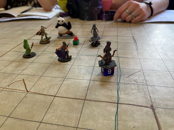 Top-down photo of a Dungeons & Dragons game setup on a wooden table with character sheets, dice, and miniatures.