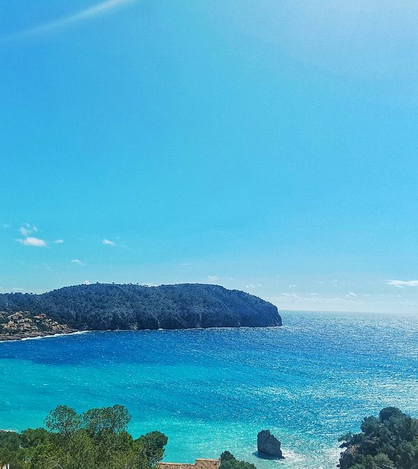 A stunning coastal view featuring a vibrant blue sea and a distant island.