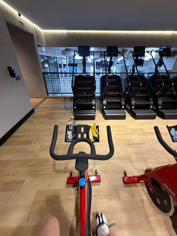 A man in gym attire flexing muscles with workout equipment in the background.