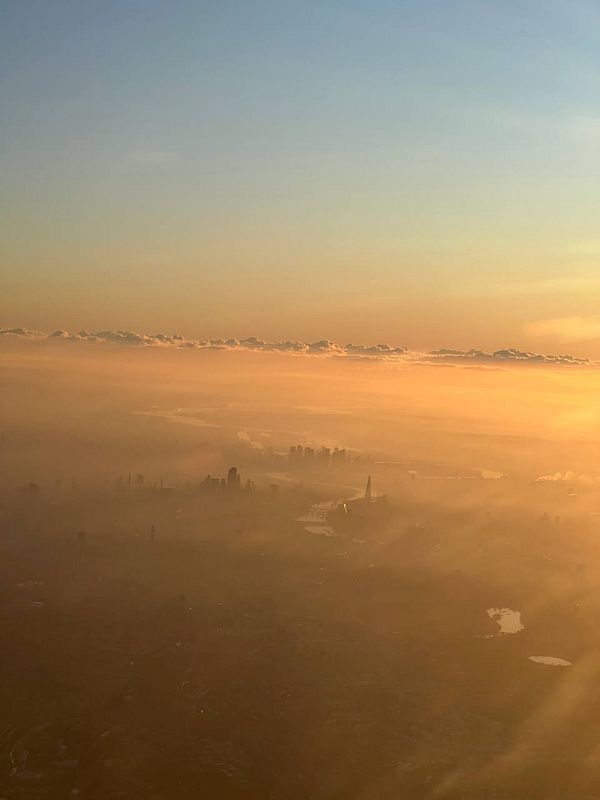 A breathtaking aerial view of a cityscape during sunset, enveloped in a golden haze.