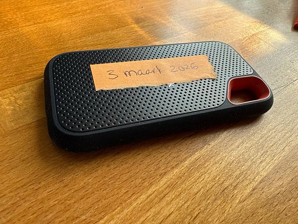 A black phone case with a label on it is resting on a wooden surface.