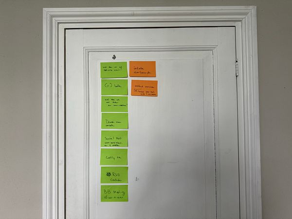 A collection of colorful sticky notes with various tasks is displayed on a white door.