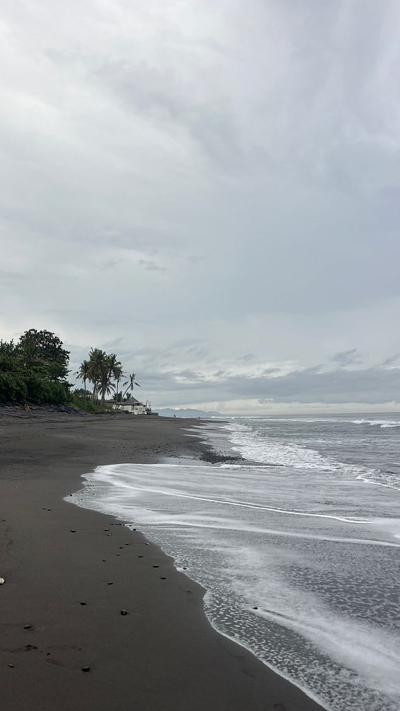 A serene beach scene in Bali under a cloudy sky.