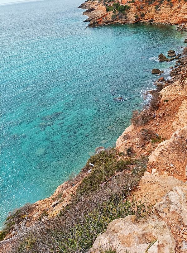 A scenic coastal view featuring clear turquoise waters and rocky cliffs.