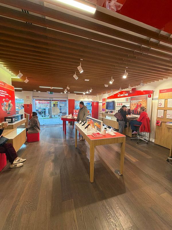 A Vodafone store interior featuring customers and various mobile devices on display.