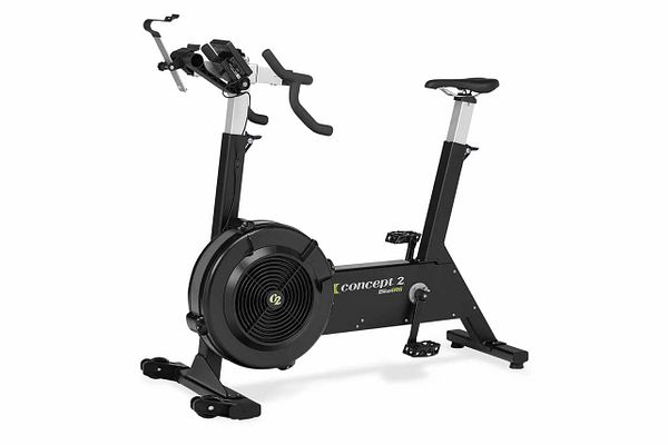 Concept2 BikeErg stationary bike displayed indoors near a window with wooden flooring.