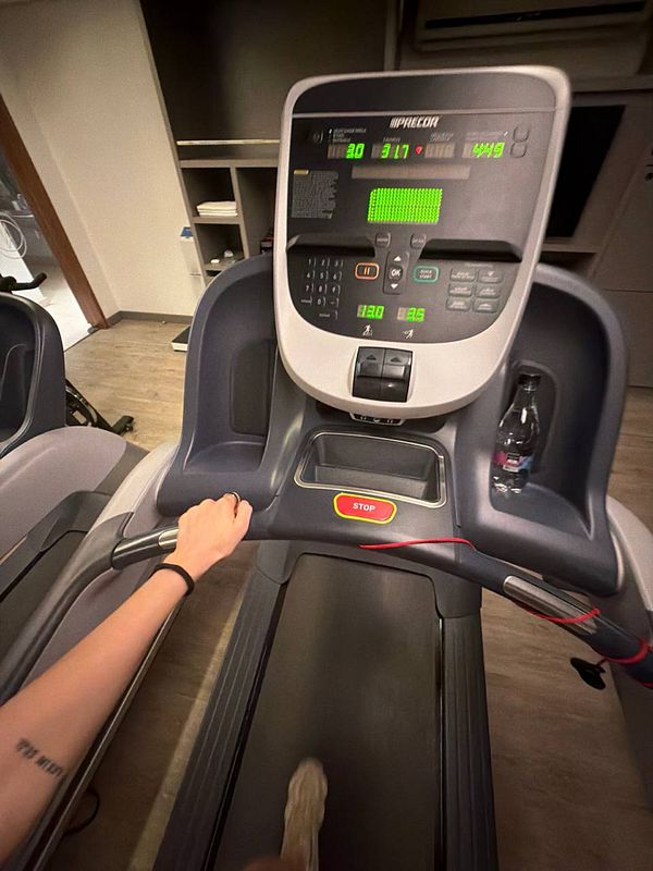 A woman in gym attire is lifting a barbell with weights in an indoor gym setting.