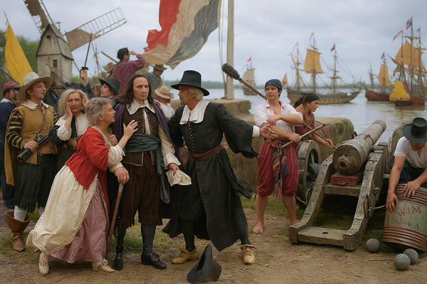 A historical scene depicting a lively gathering near a waterfront with ships in the background.