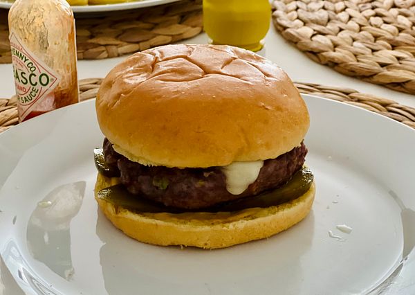 A delicious homemade burger is presented on a white plate.