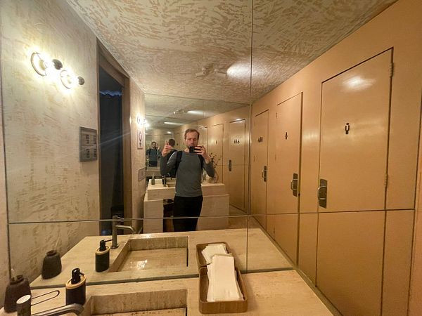 Stylish restroom interior of a cafe in Mexico City featuring a modern sink area with round mirrors and decorative vertical stripes.